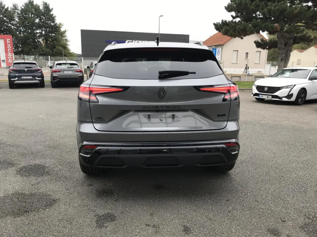Vue arrière d’un Renault Austral gris bi-ton avec feux LED fins et hayon motorisé sur parking extérieur.