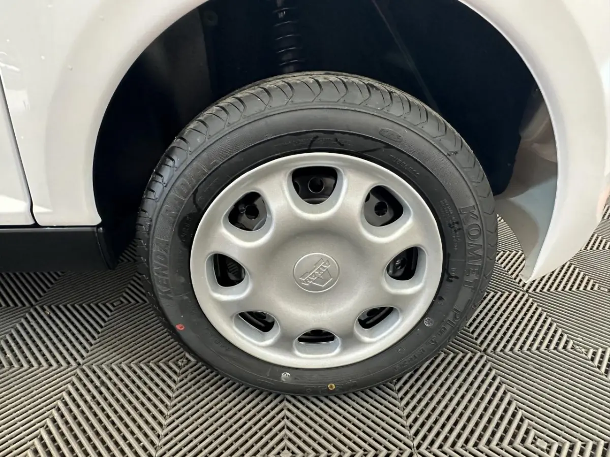 Gros plan sur la roue arrière droite d'une Aixam Minauto E Access blanche 2026 avec pneu Kenda visible.
