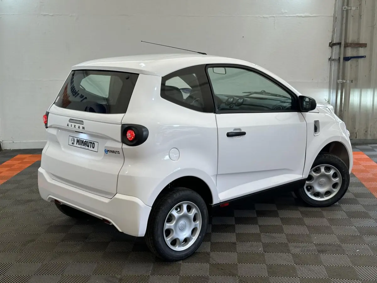 Vue 3/4 arrière droite d'une Aixam Minauto E Access blanche avec rétroviseur caméra côté conducteur.