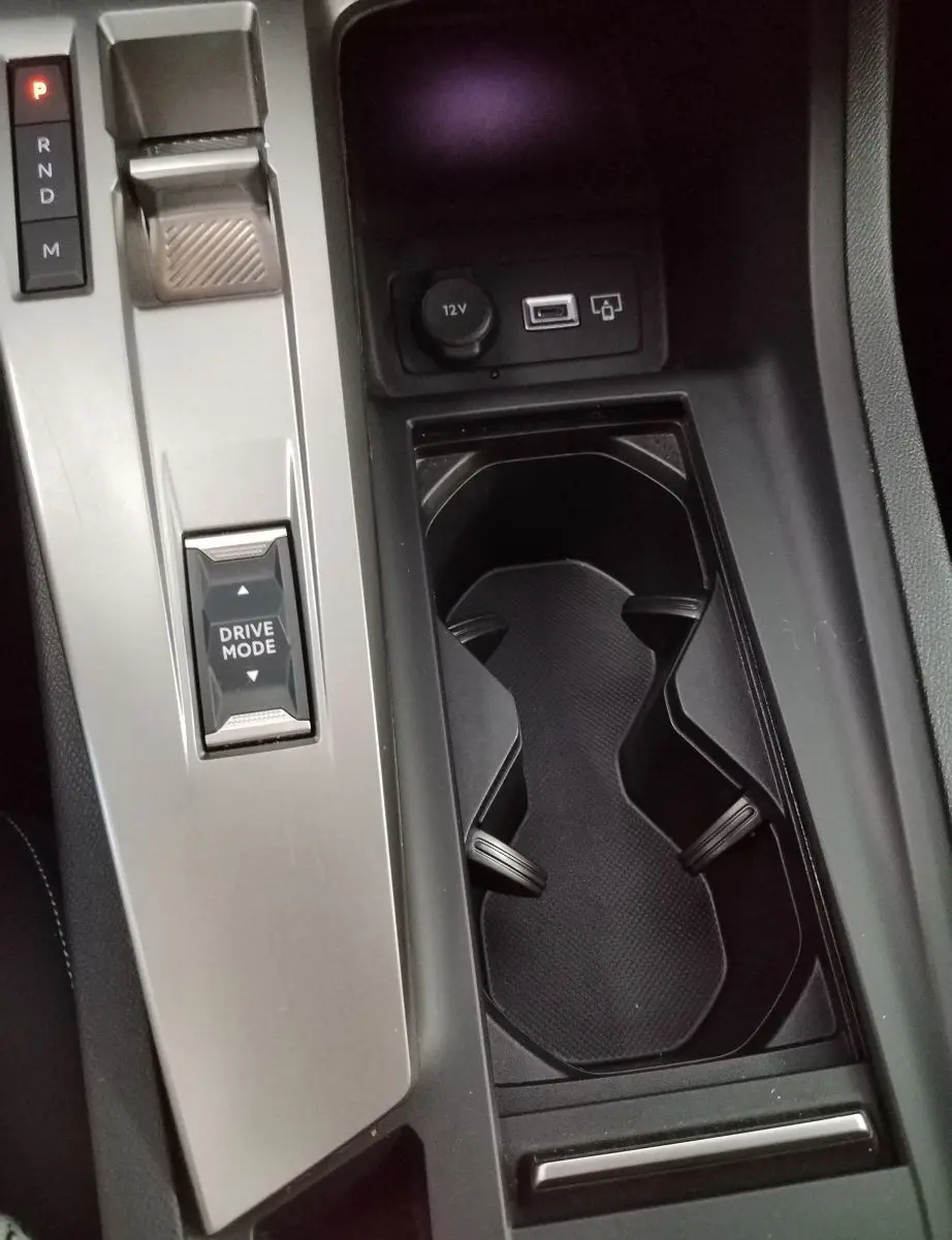 Vue rapprochée de la console centrale gris Artense du Peugeot 308 SW Hybrid avec sélecteur de mode de conduite et porte-gobelets.