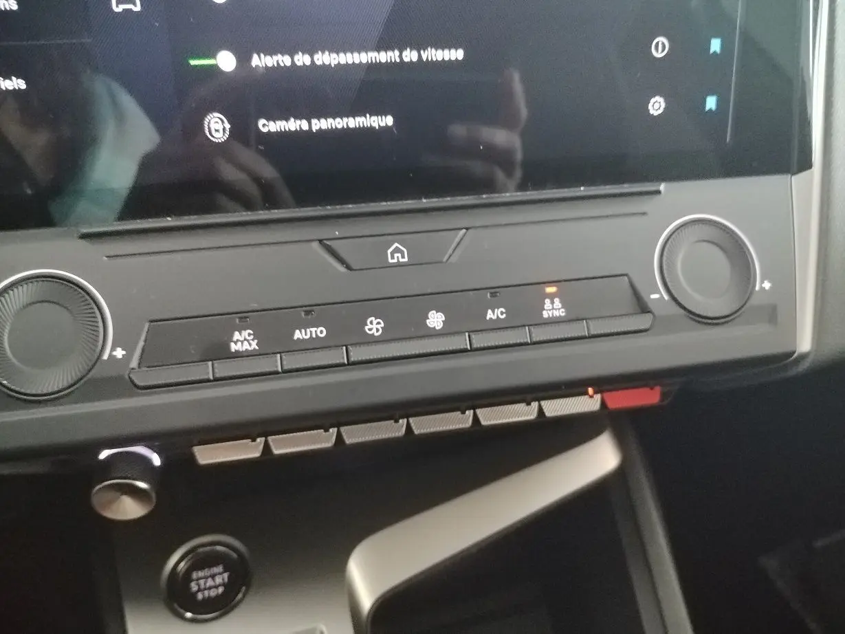 Détail du tableau de bord de la Peugeot 308 SW Hybrid 145 e-DCS6 Allure 2025 en gris Artense, montrant les commandes de climatisation et le bouton start/stop.