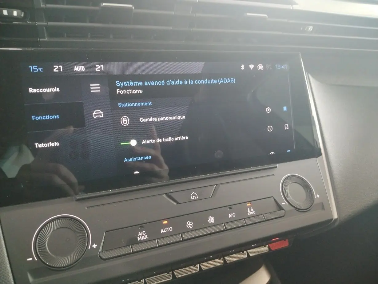 Vue rapprochée de l'écran tactile central et de la console de climatisation d'une Peugeot 308 SW Hybrid gris Artense.