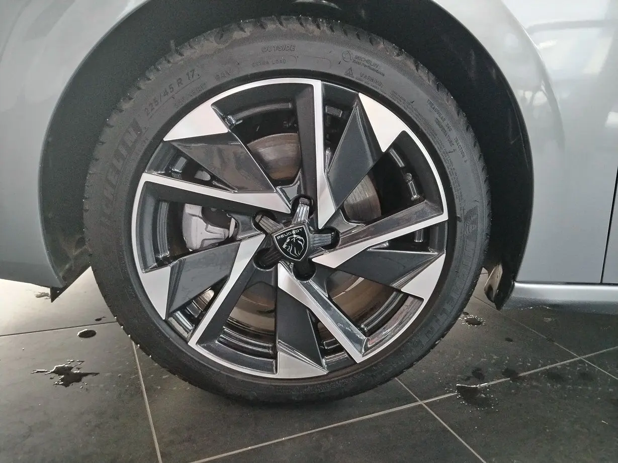 Gros plan sur la jante alliage bicolore noire et argentée d'une Peugeot 308 SW Hybrid 145 gris Artense.