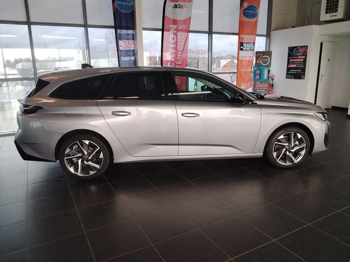 Peugeot 308 SW Hybrid 145 e-DCS6 Allure gris Artense vue de profil côté gauche en intérieur showroom.