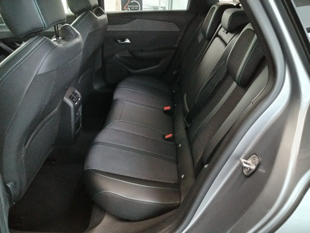 Vue côté droit de l'habitacle arrière du Peugeot 308 SW Hybrid 145 gris Artense, sièges en cuir et tissu noir avec surpiqûres.