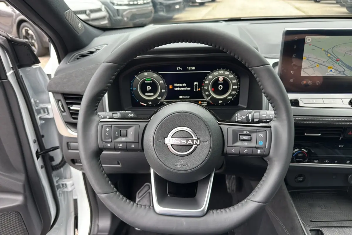 Vue intérieure centrée sur le volant cuir multifonctions d’un Nissan Qashqai E-POWER 205 Tekna Plus blanc lunaire.
