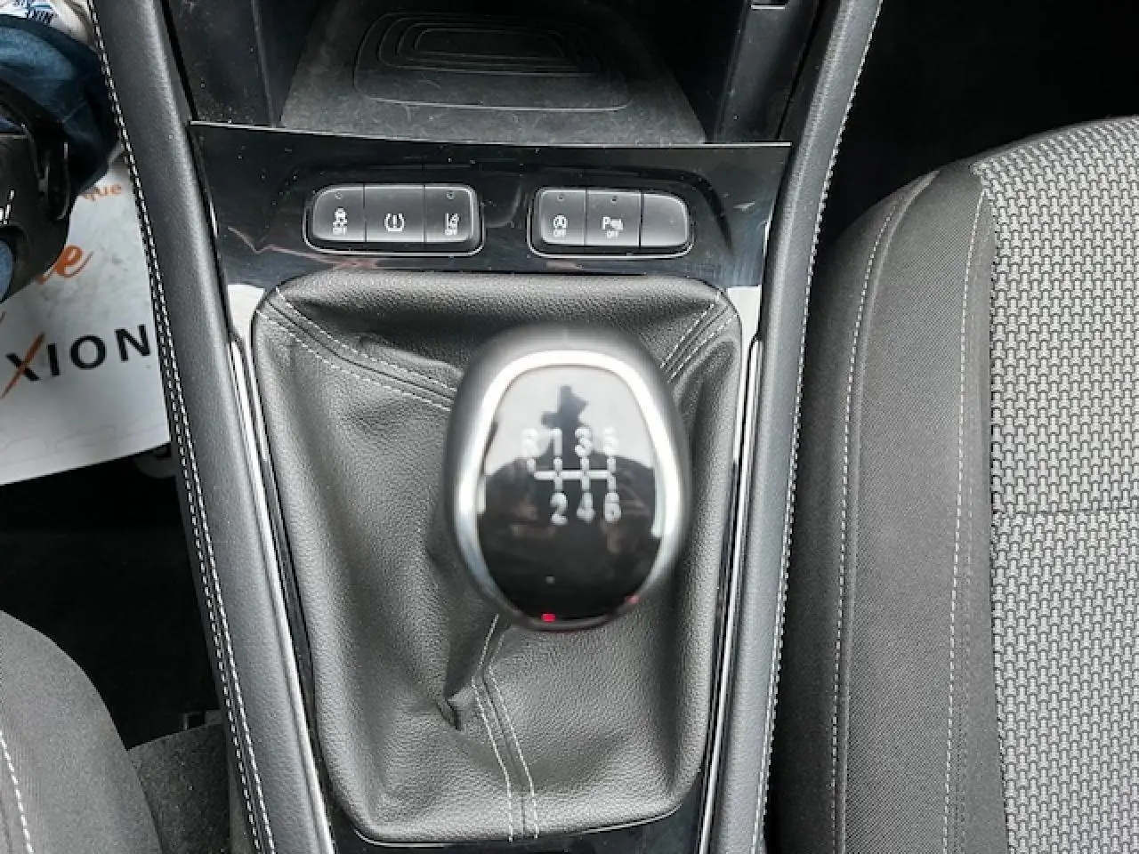 Gros plan sur le levier de vitesses manuel d'un Opel Grandland X gris, avec boutons de commande et siège tissu visible.