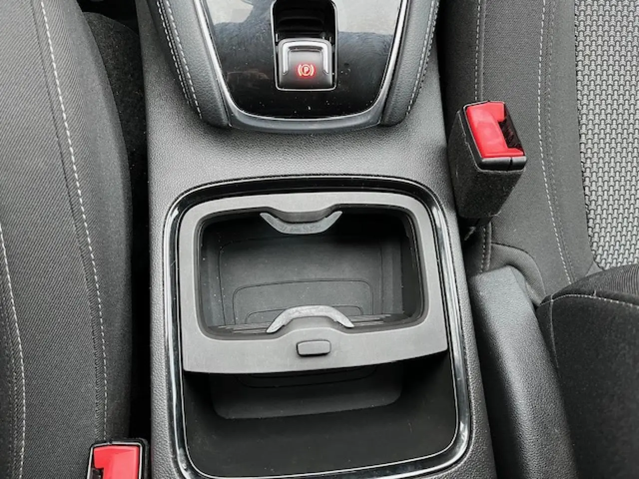 Vue plongeante sur la console centrale de l’Opel Grandland X gris, avec frein à main et rangement vide visible.
