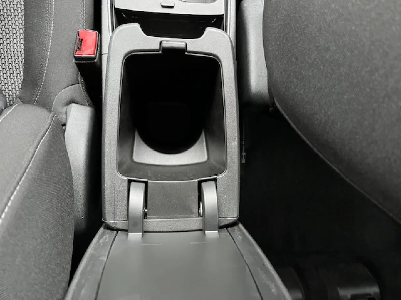 Vue en plongée sur le rangement central ouvert entre les sièges avant noirs de l'Opel Grandland X gris édition Business 2020.