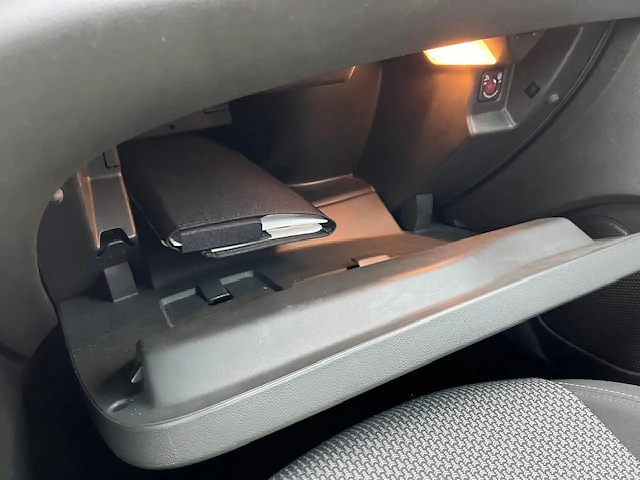 Intérieur de la boîte à gants ouverte de l’Opel Grandland X 2020, éclairage intérieur et livret visible.