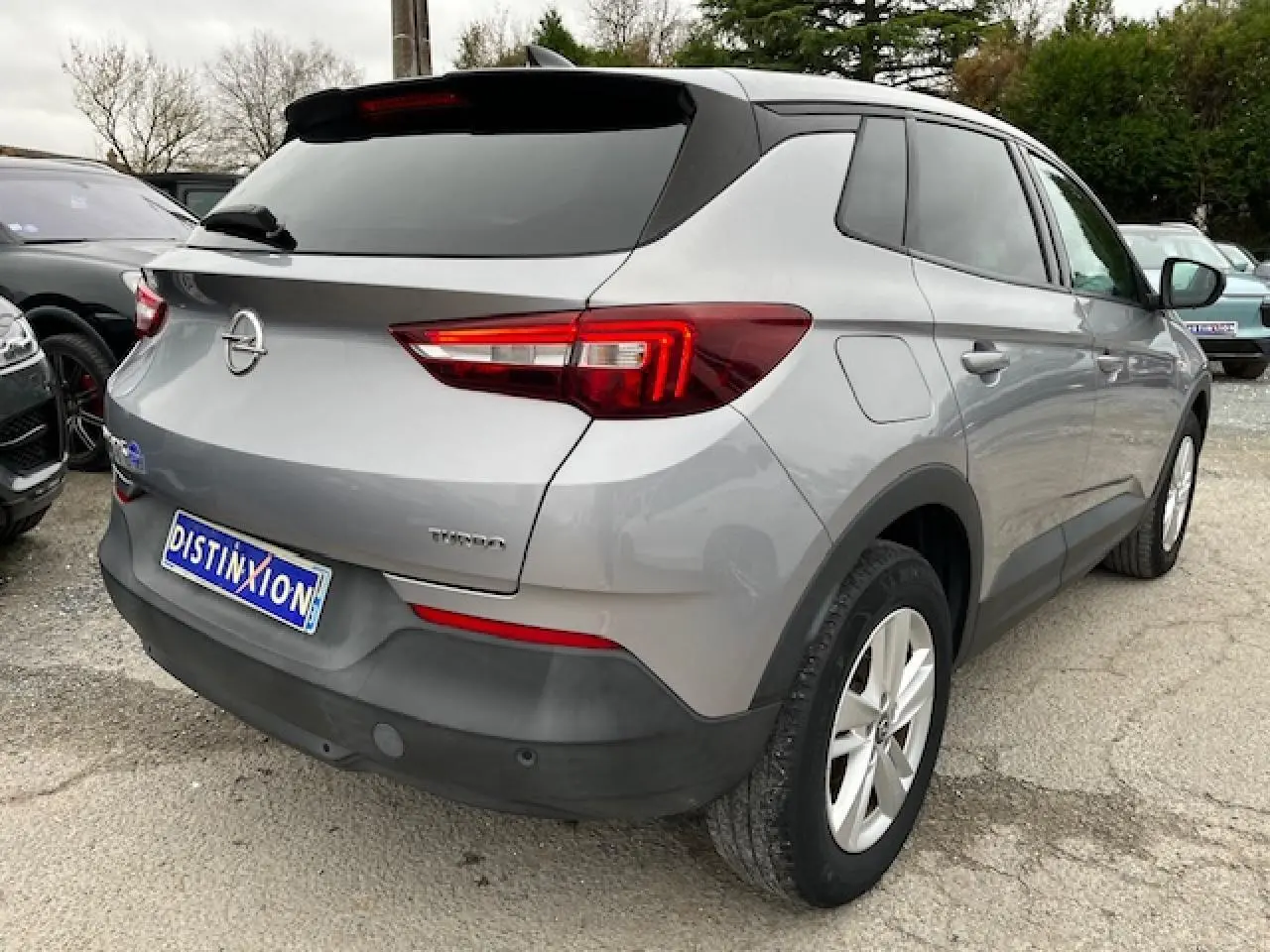Vue 3/4 arrière droite d'un Opel Grandland X gris 2020 avec feux arrière LED et badge Edition Business visible.