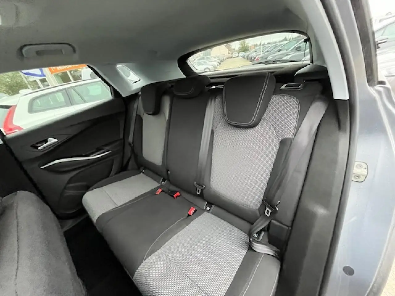 Vue intérieure de la banquette arrière de l'Opel Grandland X 2020 gris, avec sièges bi-matière et ceintures visibles.