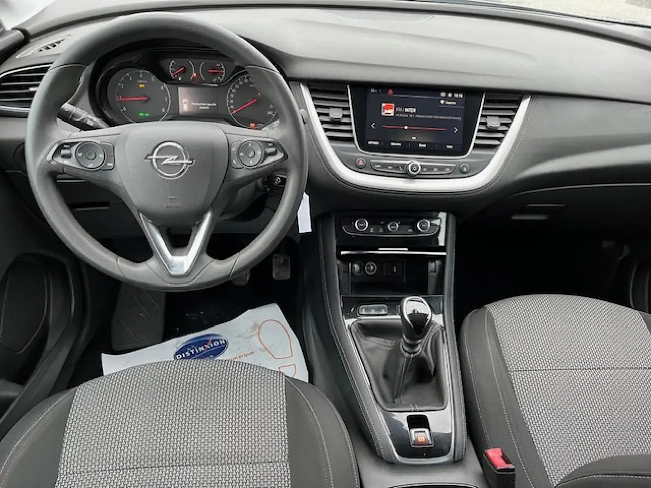 Vue intérieure avant de l'Opel Grandland X 2020 gris, montrant le volant, tableau de bord et levier de vitesses manuel.