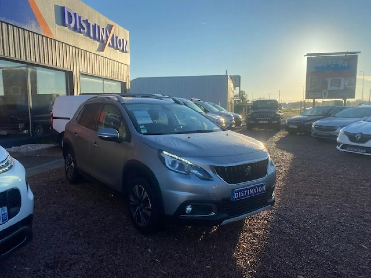 Peugeot 2008 gris Artense vue 3/4 avant droit sur parking avec jantes aluminium et calandre noire distinctive.