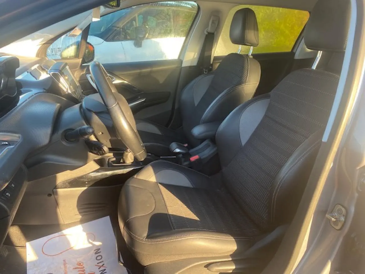 Vue intérieure côté conducteur du Peugeot 2008 gris Artense de 2019, montrant les sièges TEP et tissu, le volant et la console centrale.
