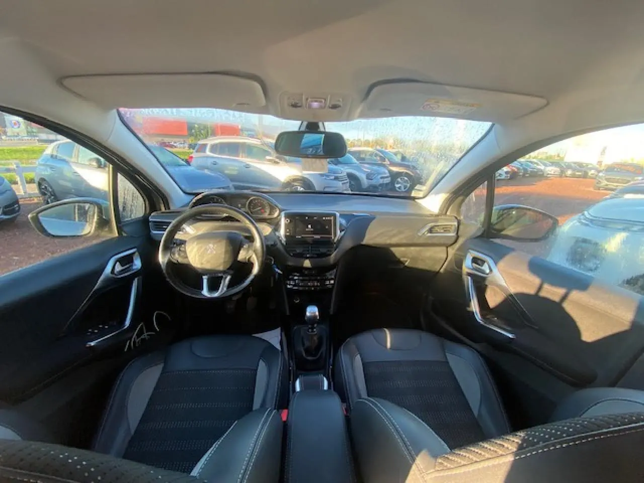 Vue intérieure avant de la Peugeot 2008 gris Artense 2019, avec tableau de bord moderne et volant multifonctions.