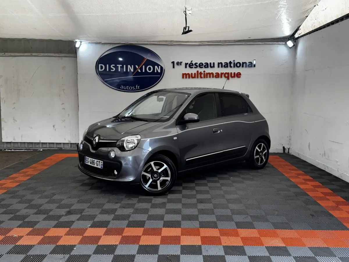 Renault Twingo Intense Energy gris foncé vue 3/4 avant droit dans un garage avec sol à damiers gris et orange.