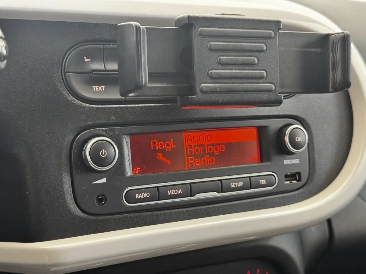 Gros plan sur la console centrale noire et beige de la Renault Twingo Intense Energy TCe 90 avec écran radio rouge allumé.