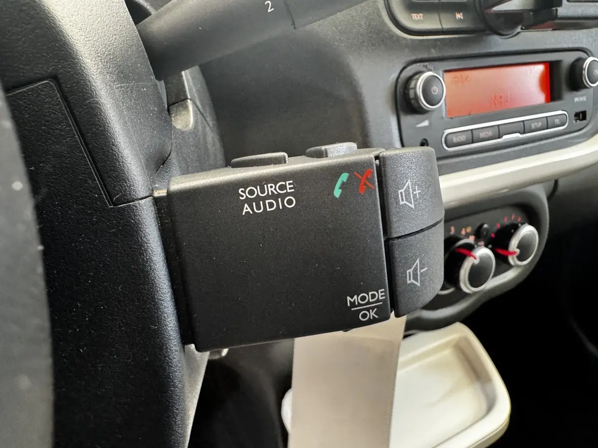 Gros plan sur la commande audio au volant côté gauche dans l’habitacle gris foncé de la Renault Twingo Intense Energy 2016.
