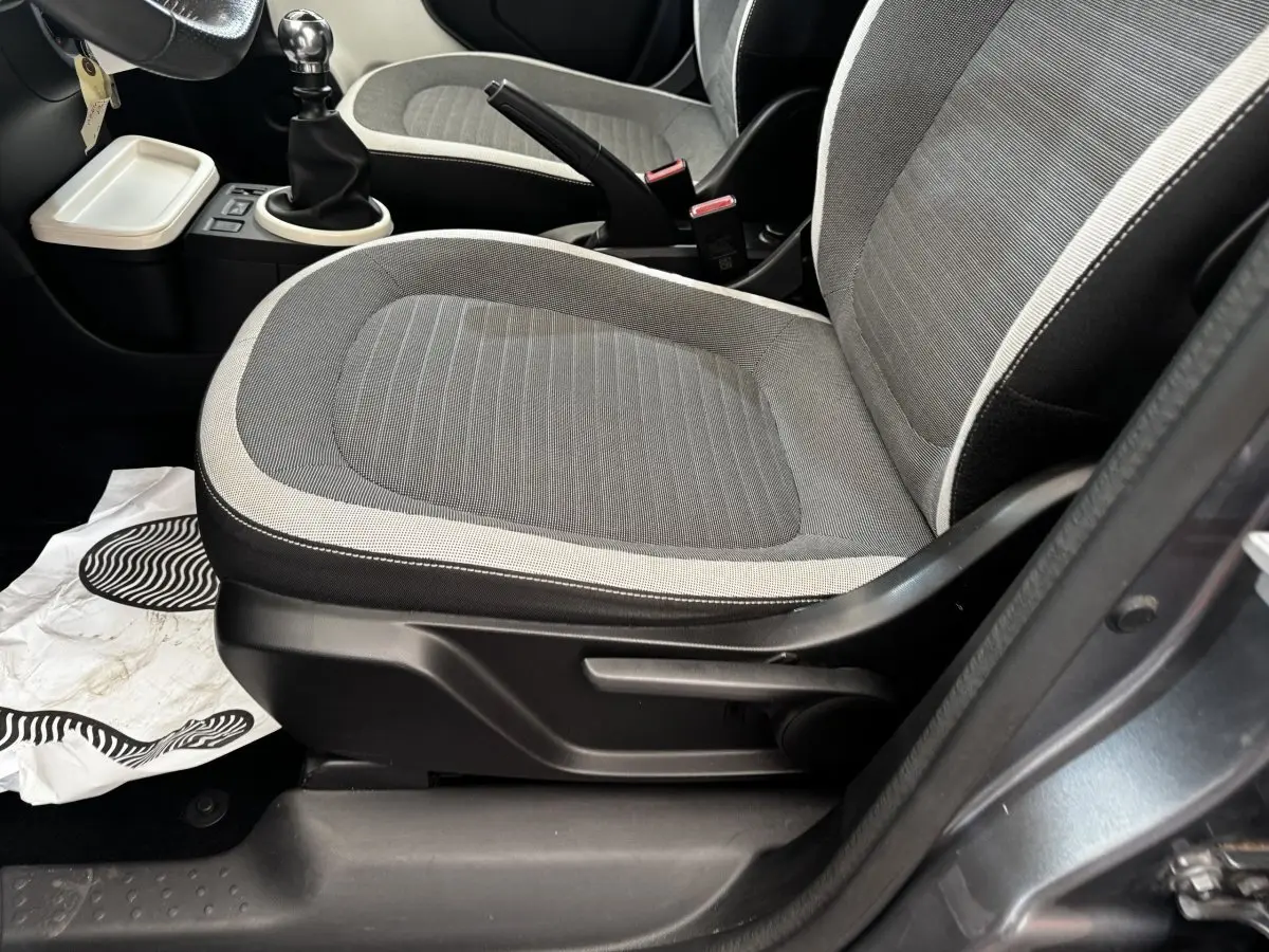 Vue rapprochée du siège avant droit gris clair avec contours sombres et levier de frein à main d’une Renault Twingo 2016.
