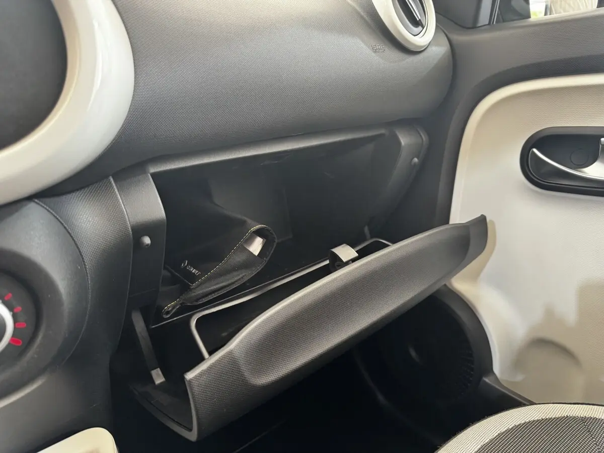 Vue intérieure côté passager de la Renault Twingo Intense Energy TCe 90 2016, boîte à gants ouverte avec pochette noire visible.