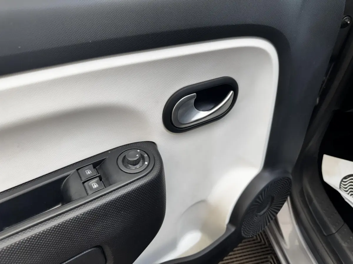 Gros plan sur la porte intérieure avant gauche gris clair de la Renault Twingo Intense Energy TCe 90 avec commandes électriques.