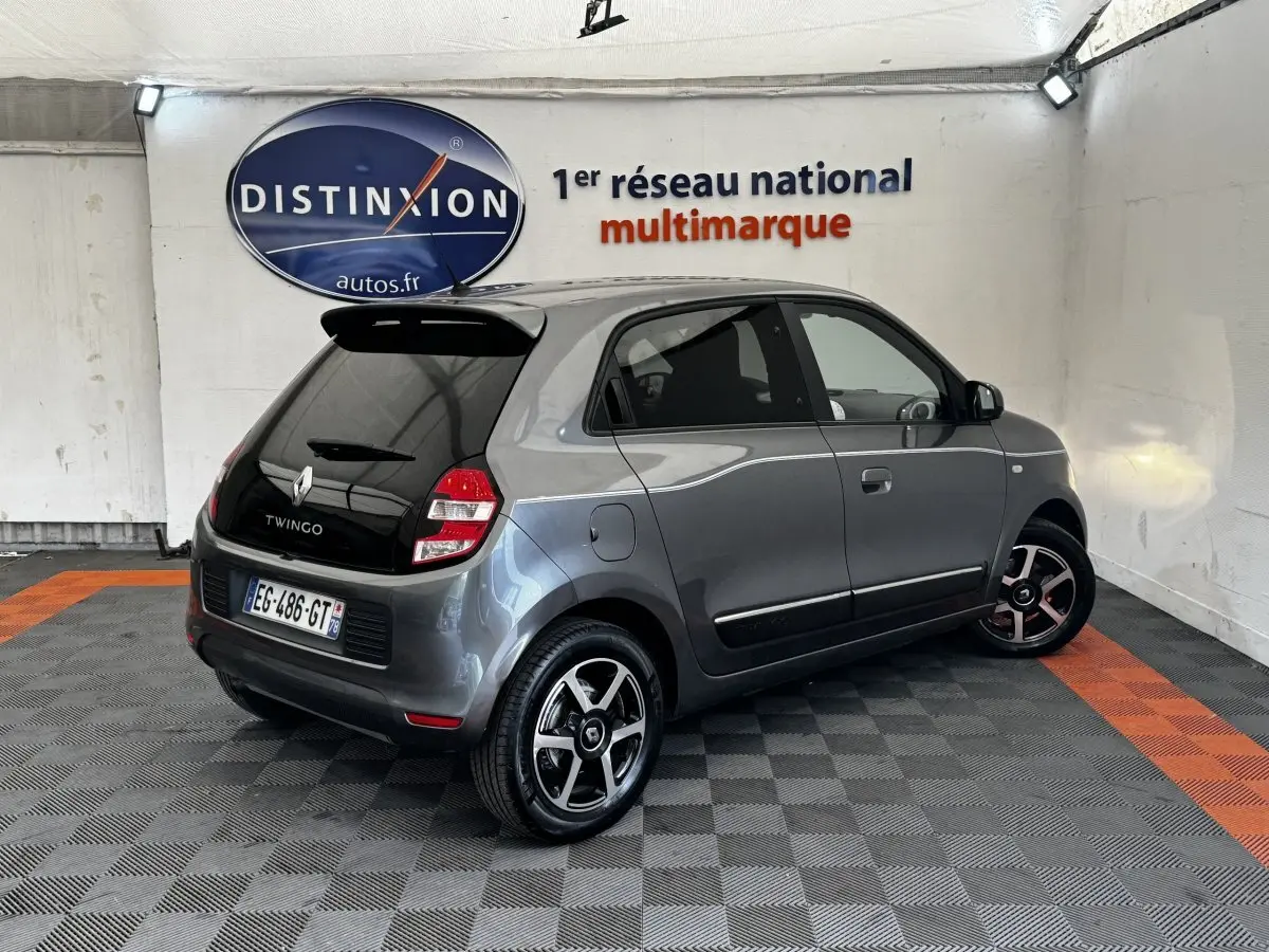 Renault Twingo gris foncé vue 3/4 arrière droit, avec toit noir et jantes alliage bicolores.