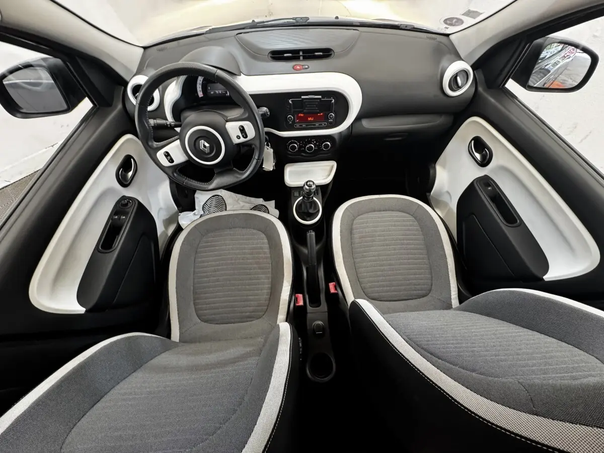 Vue intérieure avant de la Renault Twingo gris foncé, montrant le tableau de bord, volant cuir et sièges tissu gris.