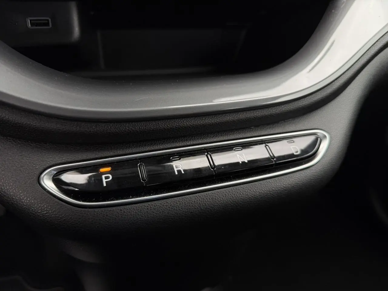 Gros plan sur la commande de boîte automatique avec boutons P, R, N, D éclairé en orange dans une Fiat 500 électrique blanche.