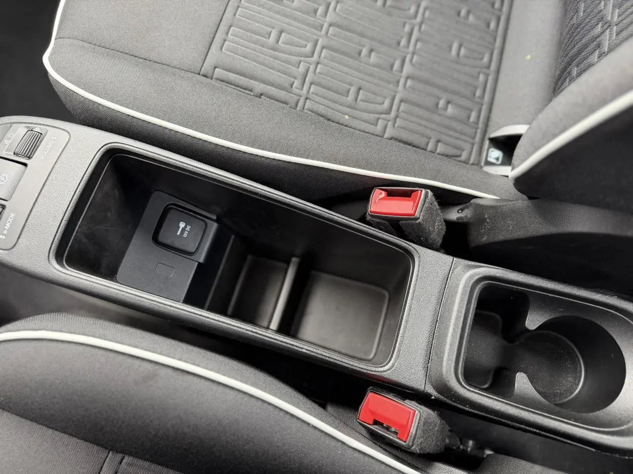 Gros plan sur la console centrale et les sièges noirs avec surpiqûres blanches de la Fiat 500 électrique 2024.