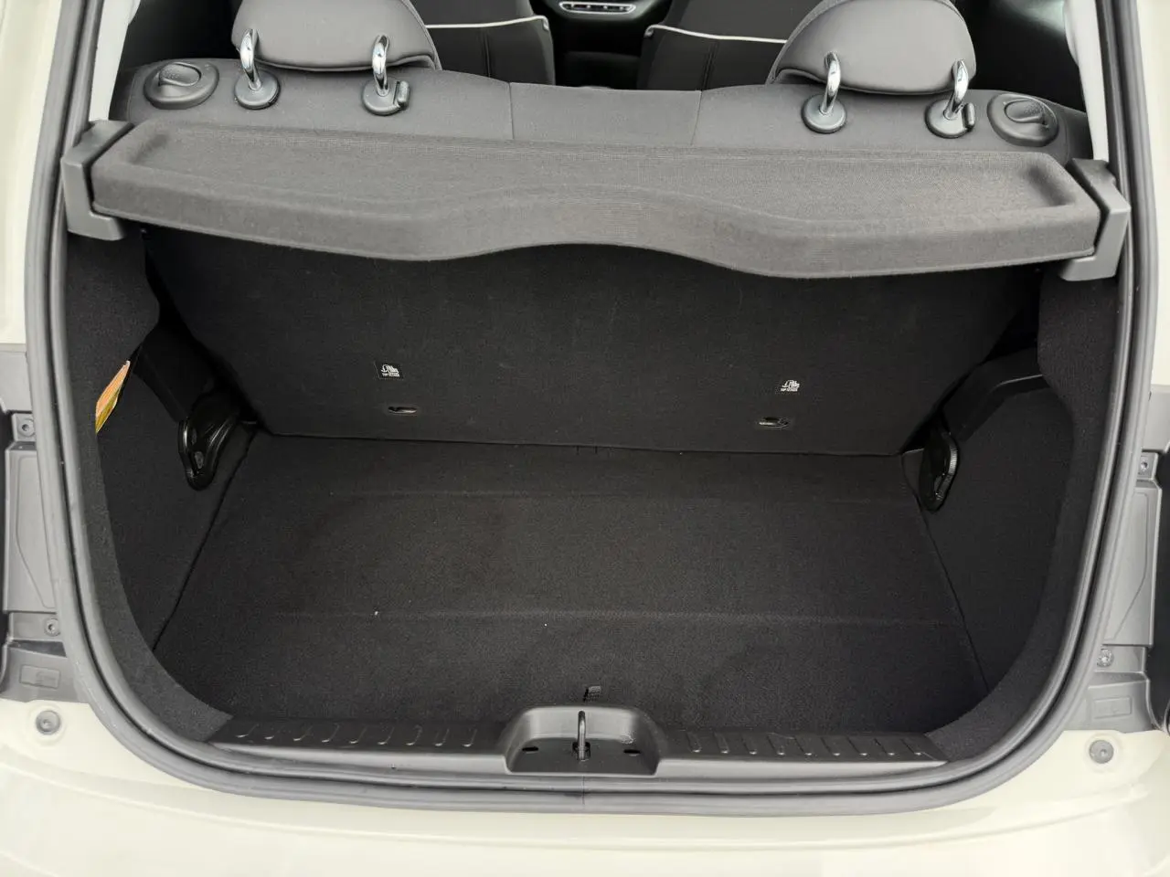 Coffre ouvert vu de l'arrière d'une FIAT 500 électrique blanc Artic, montrant l'espace de rangement intérieur noir.