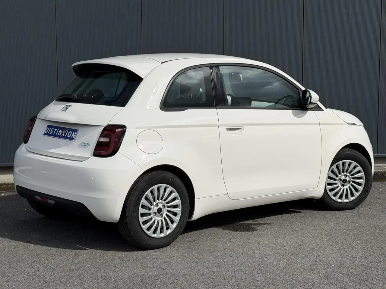 Vue 3/4 arrière droite d'une Fiat 500 électrique blanche Arctic avec feux arrière foncés et jantes multibranches.