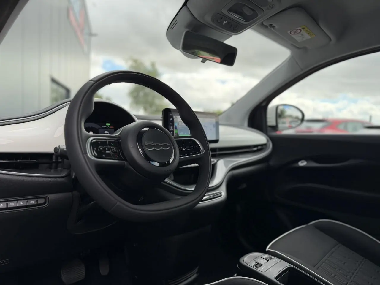 Intérieur de la Fiat 500 électrique 2024 vu côté conducteur, volant noir soft-touch et planche de bord blanc Artic.