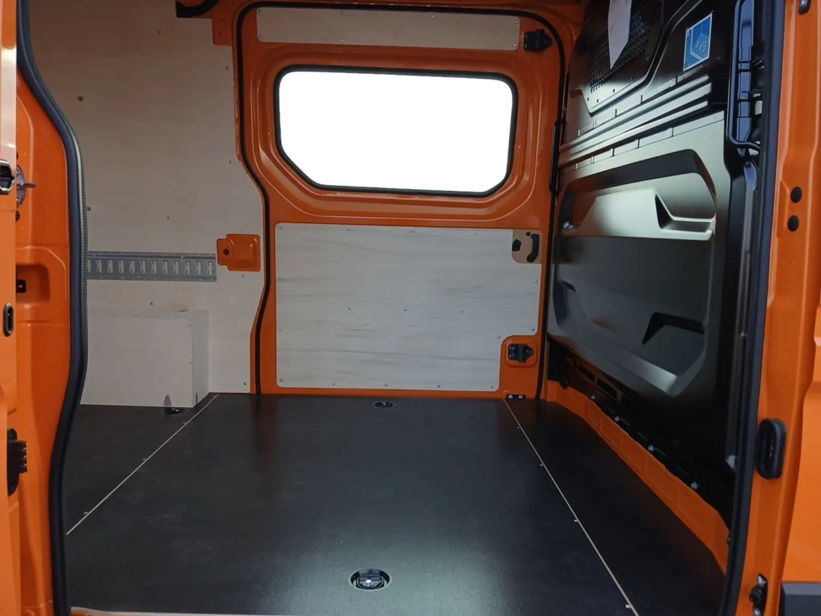 Vue intérieure arrière du Renault Master orange L2H2, montrant l'espace de chargement avec parois en bois clair.