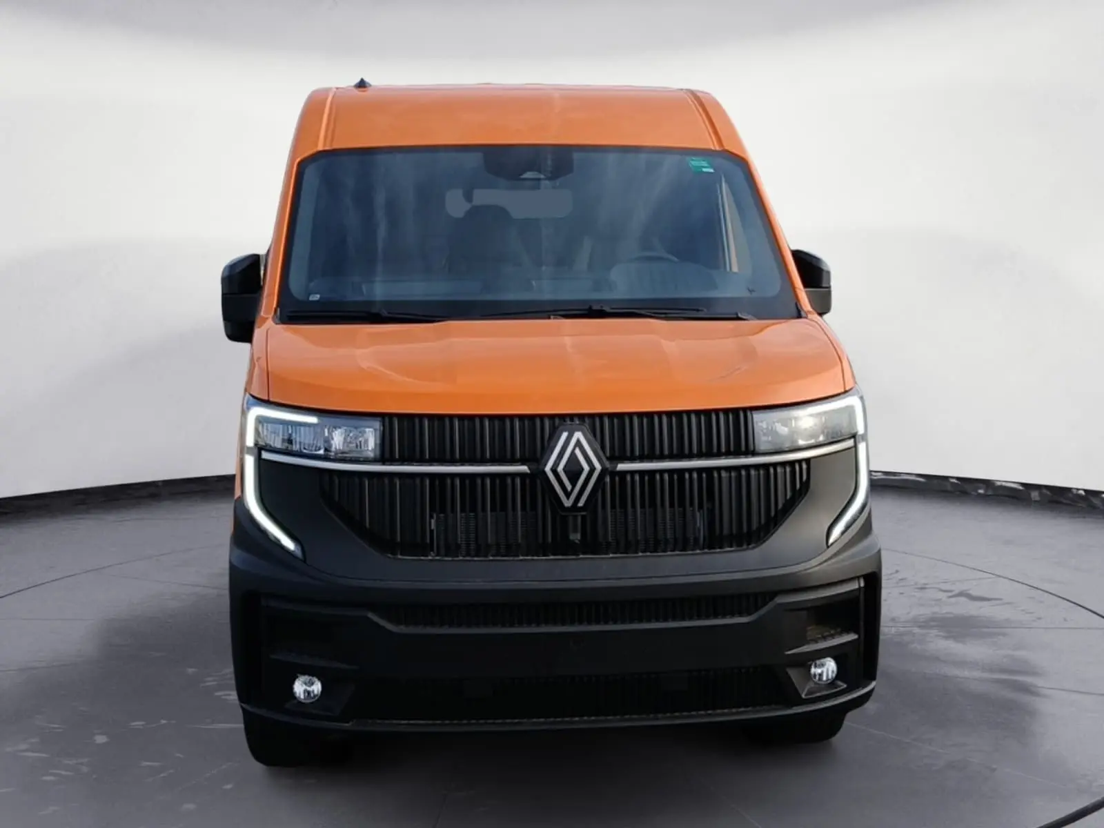 Vue frontale d’un Renault Master L2H2 orange avec calandre noire et feux LED en forme de C.