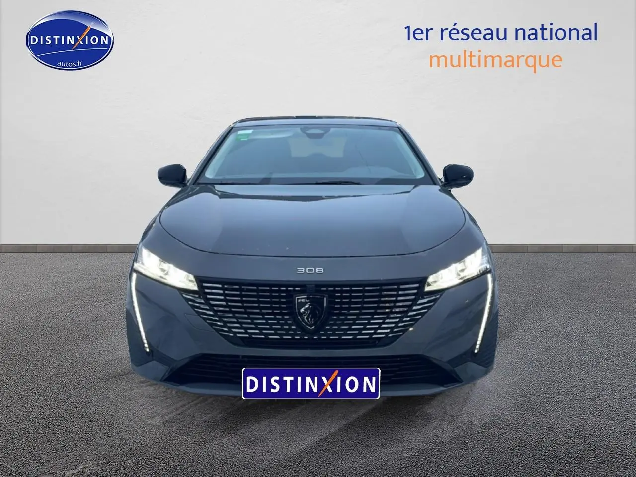 Vue frontale d'une Peugeot 308 gris sélénite 2025 avec phares LED allumés et calandre distinctive.