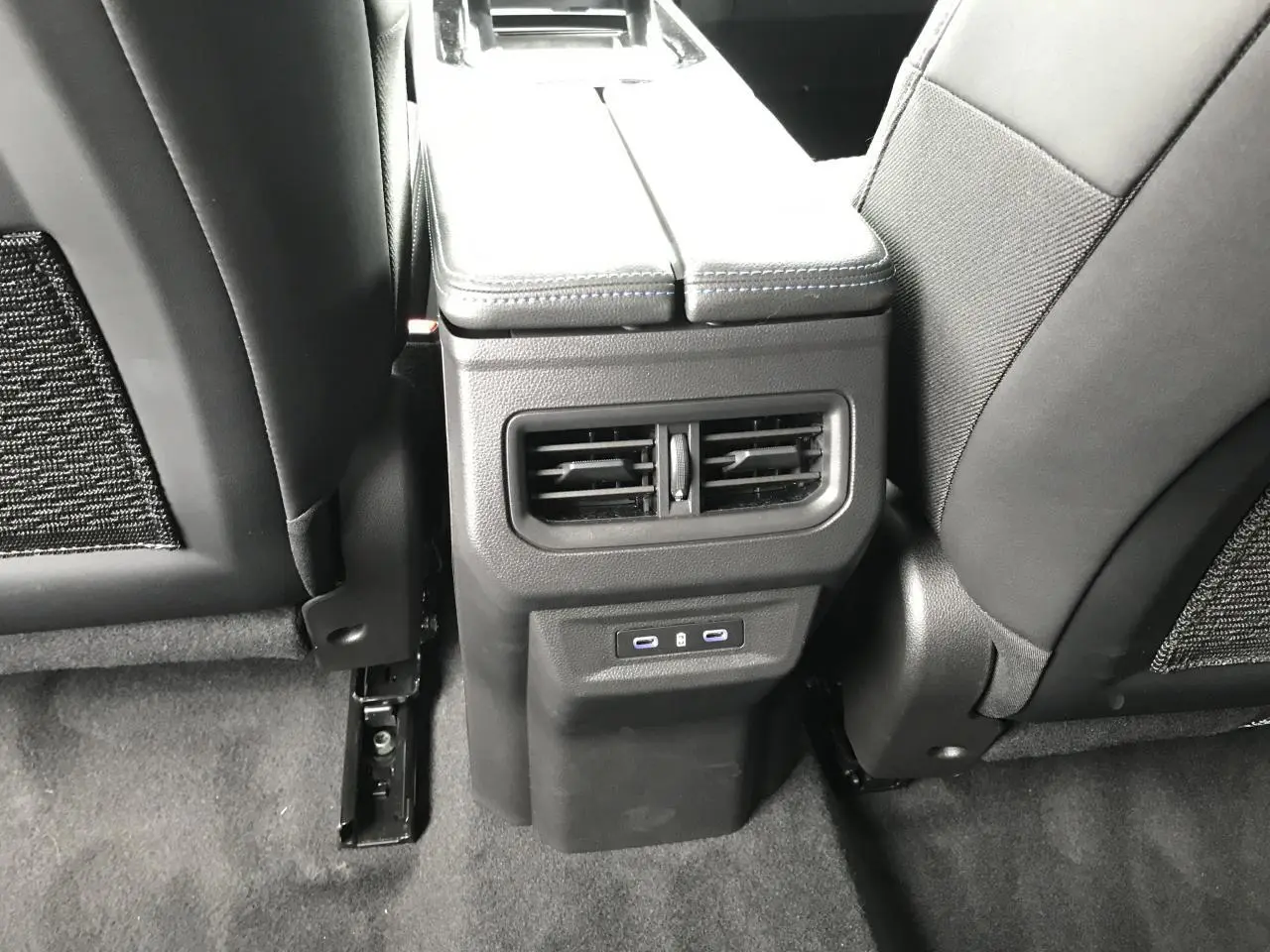 Vue rapprochée de la console centrale arrière du Renault Austral blanc, avec aérateurs et prises USB visibles.