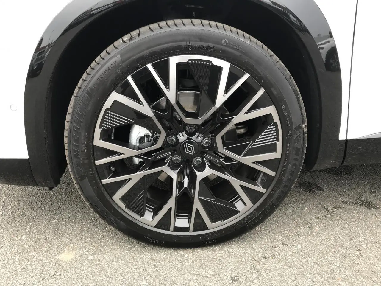 Gros plan sur la jante alliage 20'' noire et argentée du côté gauche d'un Renault Austral blanc QPB GNE.