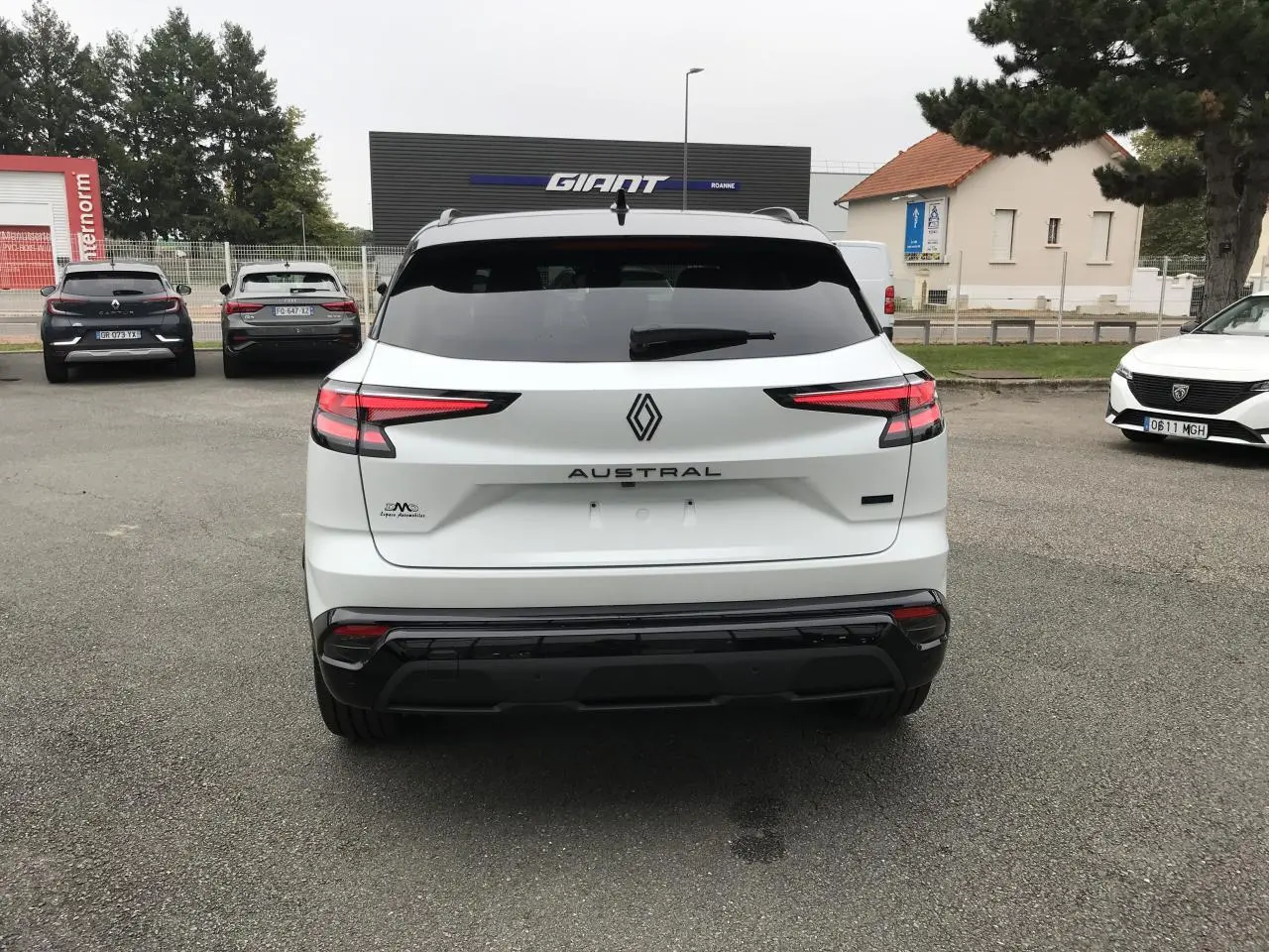 Vue arrière d'un Renault Austral blanc bi-ton avec feux arrière LED et logo central sur un parking extérieur.