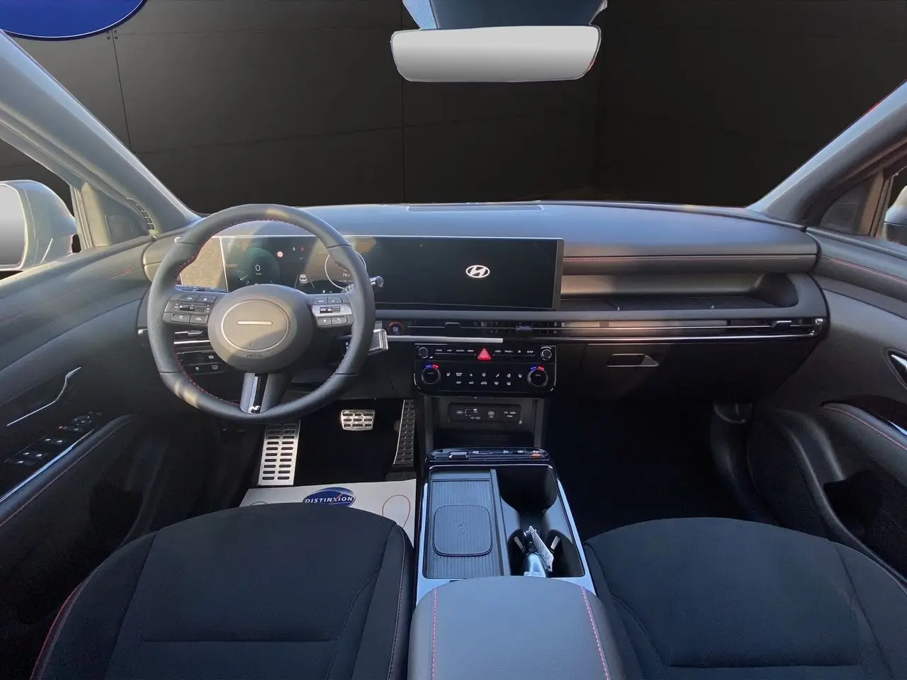 Vue intérieure avant du Hyundai Tucson 2025 noir abyss, avec tableau de bord numérique et volant multifonction.