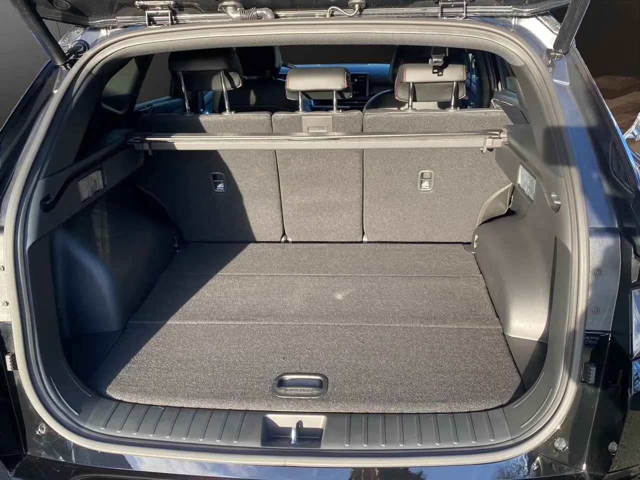 Coffre ouvert vu de l'arrière d'un Hyundai Tucson 2025 noir abyss, montrant un espace de chargement spacieux et bien fini.
