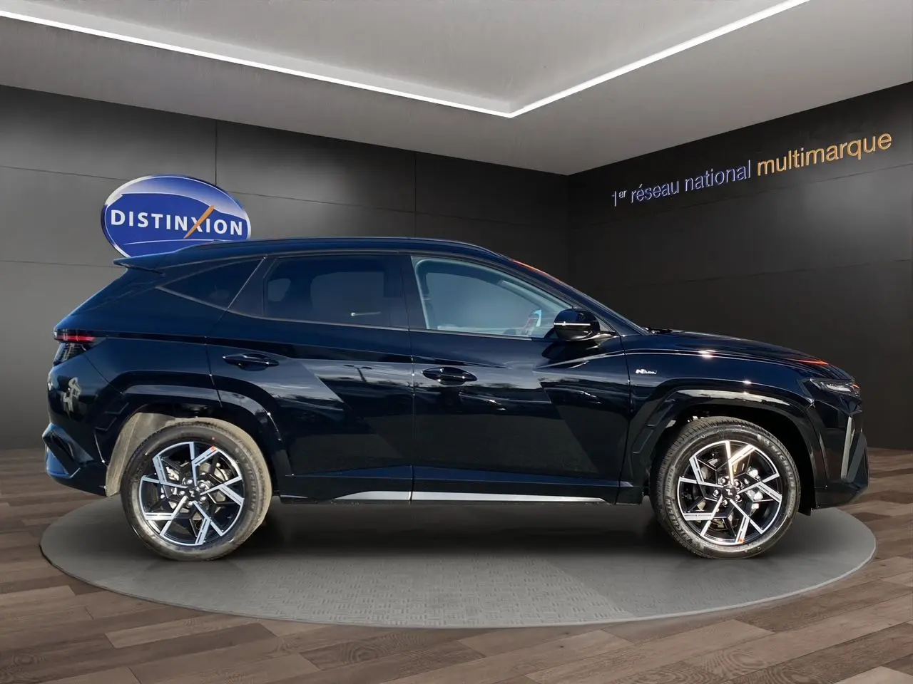 Vue de profil côté gauche du Hyundai Tucson 2025 hybride N Line Creative en noir abyss, avec jantes alliage bicolores distinctives.