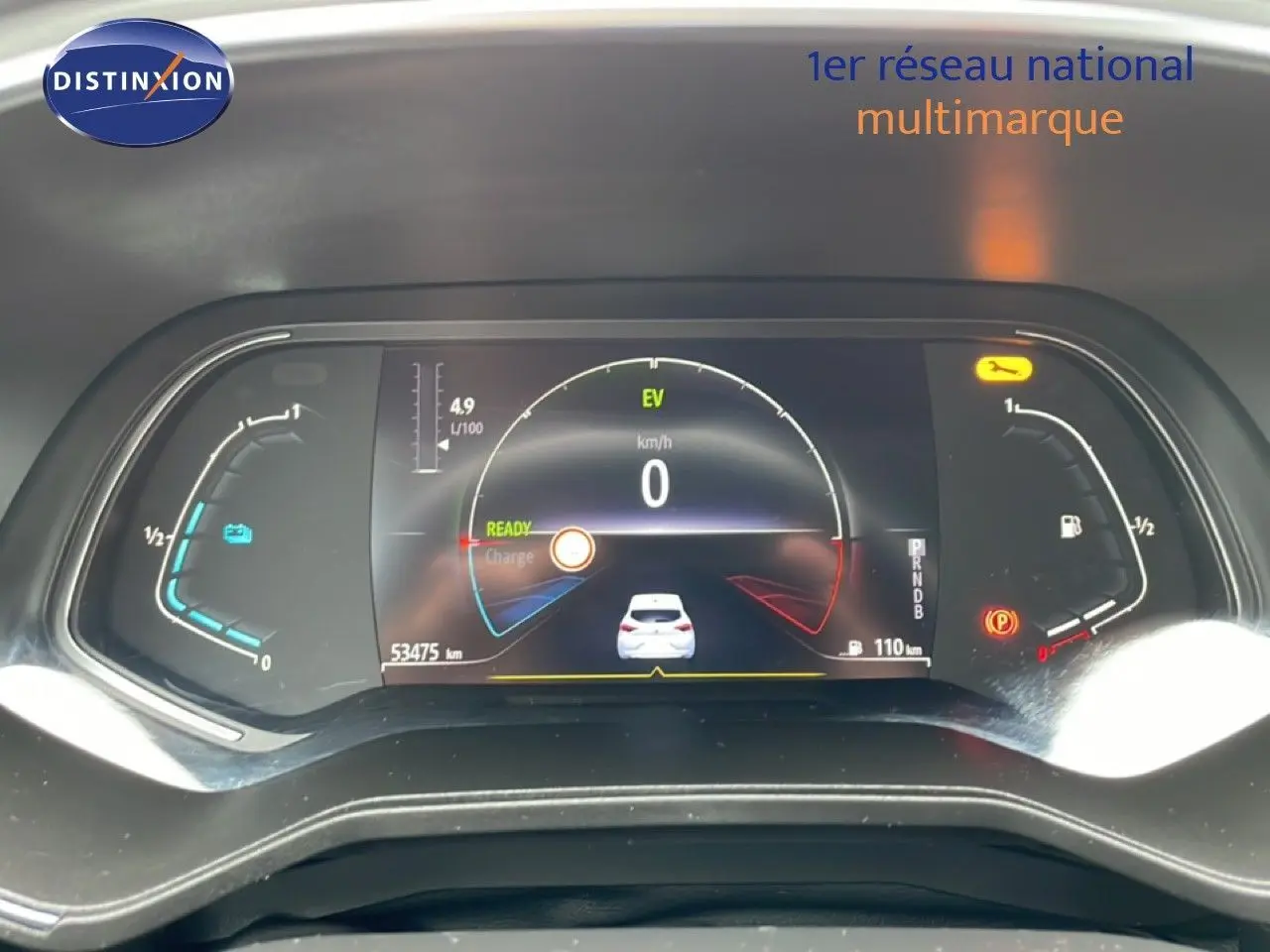 Tableau de bord numérique de Renault Clio blanc glacier, affichage vitesse à 0 km/h et jauges hybrides en vue frontale.