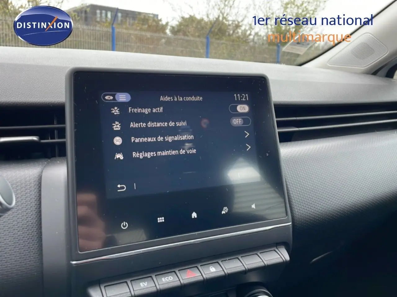 Écran tactile central affichant les aides à la conduite dans l’habitacle d’une Renault Clio blanche Glacier, vue de face.
