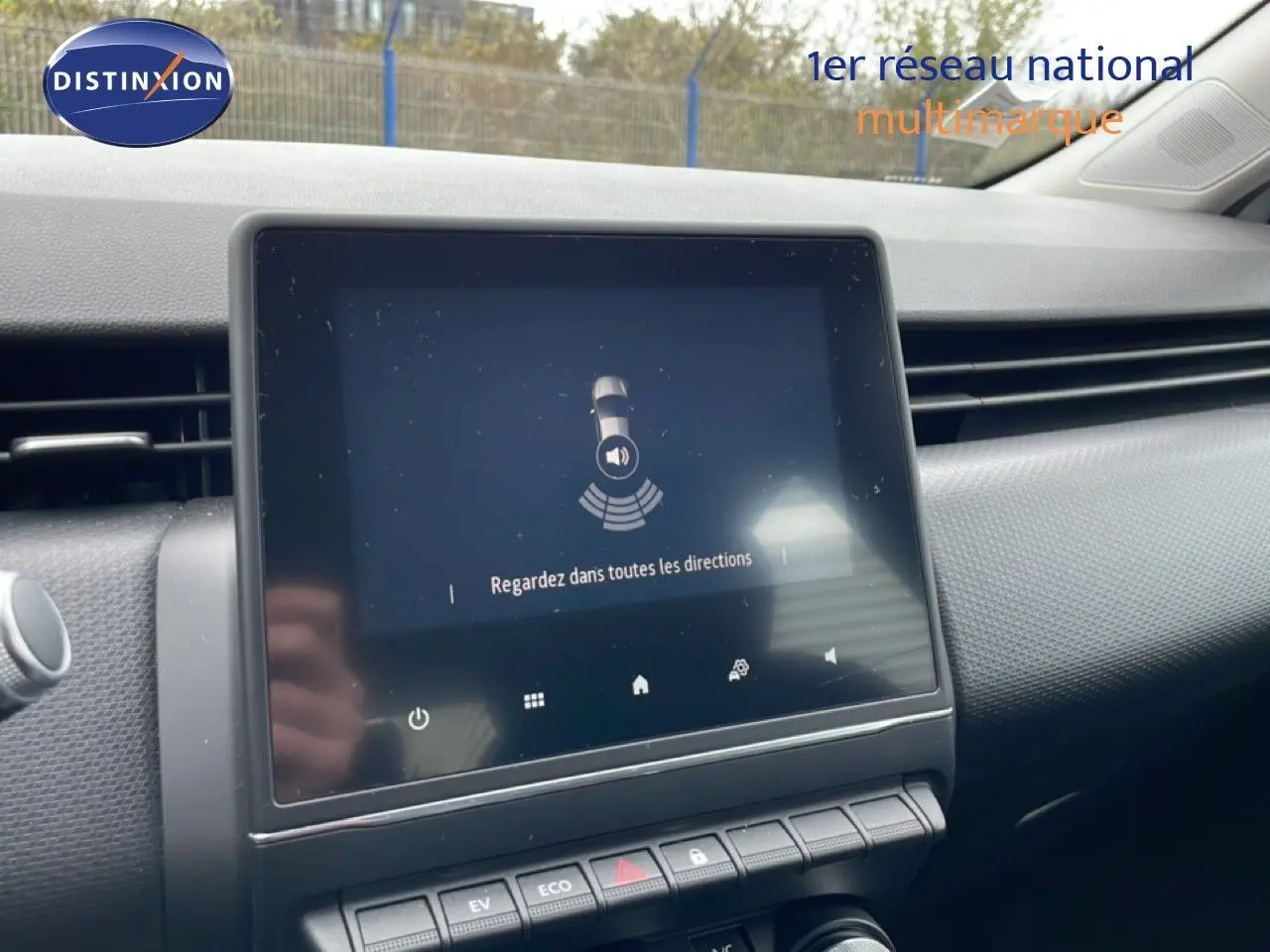 Vue rapprochée de l’écran tactile central du tableau de bord de la Renault Clio blanche, affichant une alerte de surveillance.