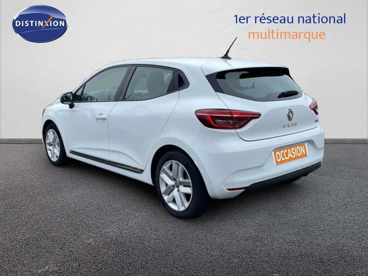 Renault Clio blanc glacier vue 3/4 arrière droit, compacte hybride essence avec jantes alliage et feux LED distinctifs.