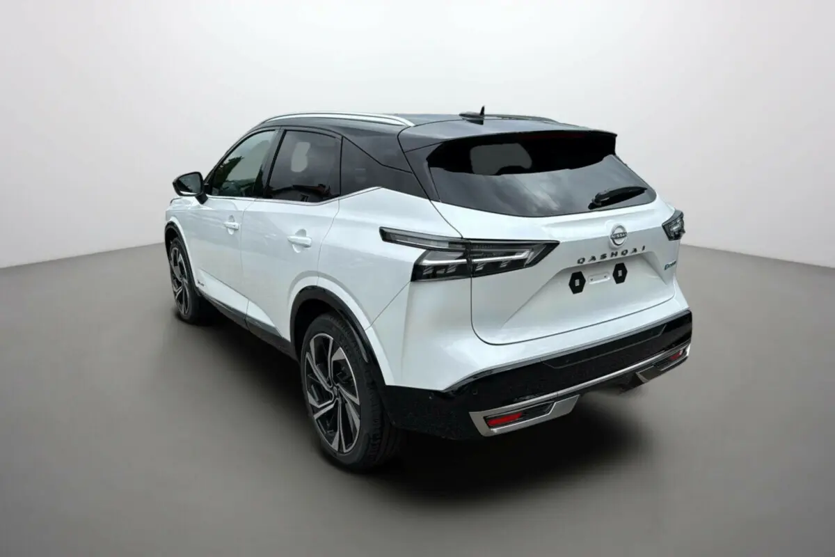 Vue 3/4 arrière droite du Nissan Qashqai blanc lunaire avec toit noir et jantes alu 20 pouces sur fond neutre.