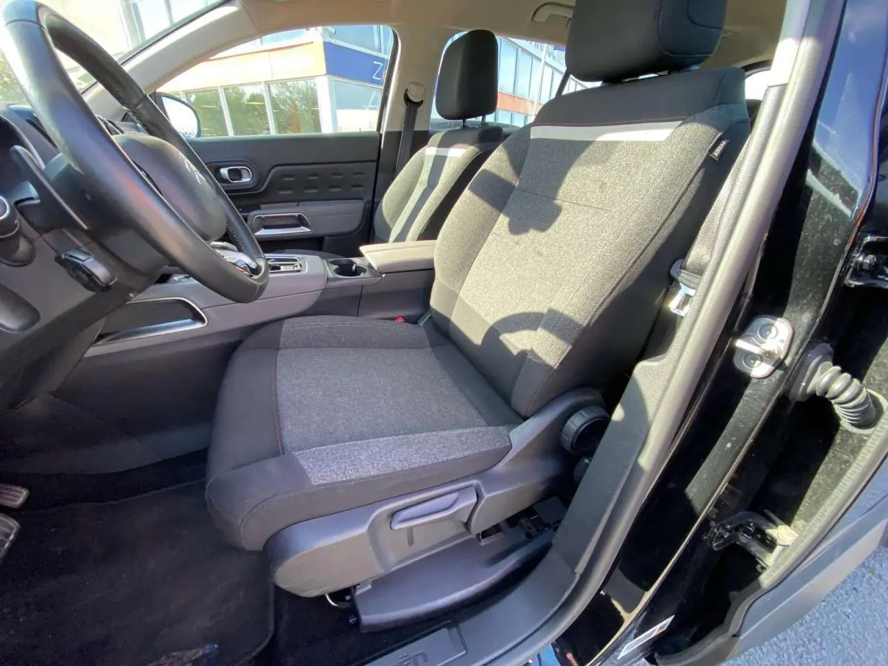 Vue intérieure côté conducteur du Citroën C5 Aircross noir 2021, mettant en valeur le siège avant en tissu gris et noir.
