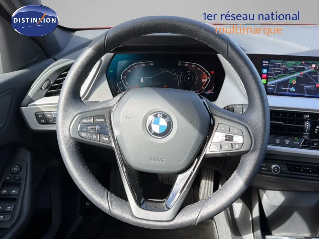 Vue intérieure centrée sur le volant noir de la BMW Série 1 116i 2022 avec tableau de bord numérique et écran tactile.