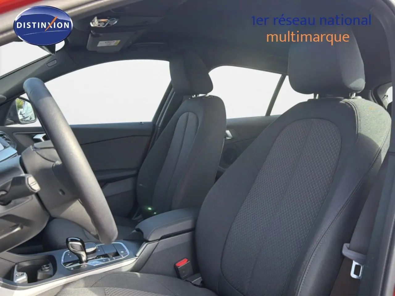 Vue intérieure côté conducteur de la BMW Série 1 116i 2022 avec sièges tissu noirs et console centrale moderne.